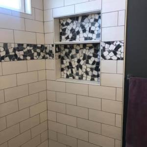 The inset shelf and wrap around tile stripe add a layer of lux to this bathroom